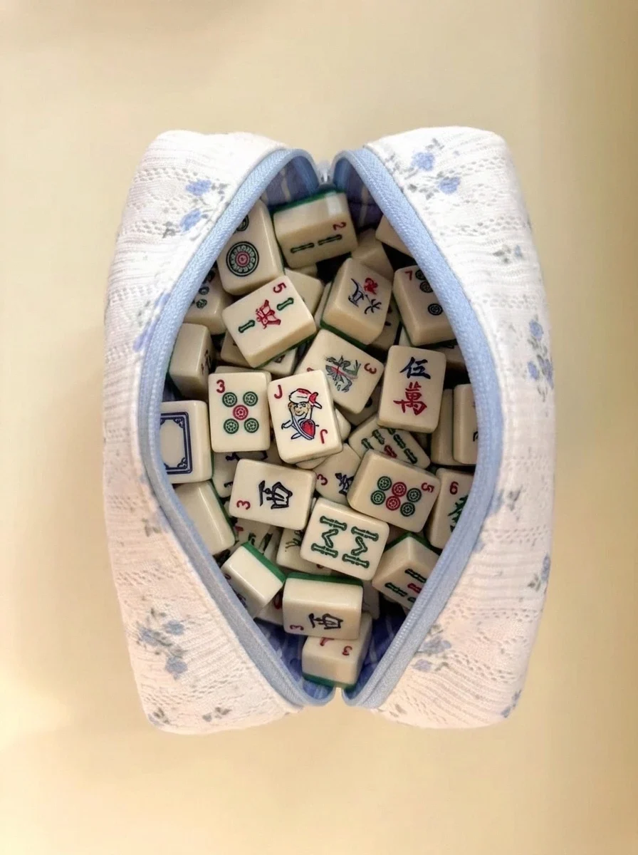 Open blue floral mahjong tile storage bag filled with mahjong tiles