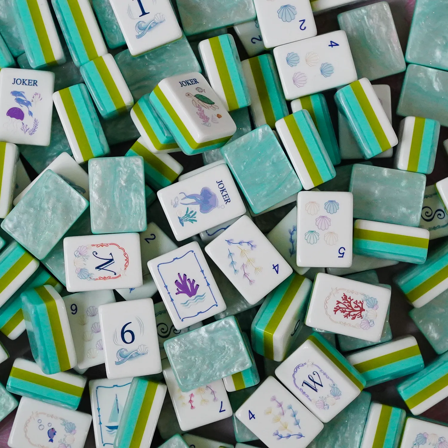 Scattered Reef Kiss acrylic mahjong tiles displaying layered construction and ocean-inspired illustrations